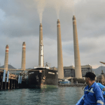 Seorang nelayan sedang mengamati pembangkit listrik tenaga batu bara (PLTN) Suralaya di Cilegon, provinsi Banten, 31 Oktober 2023. (Ronald SIAGIAN / AFP)