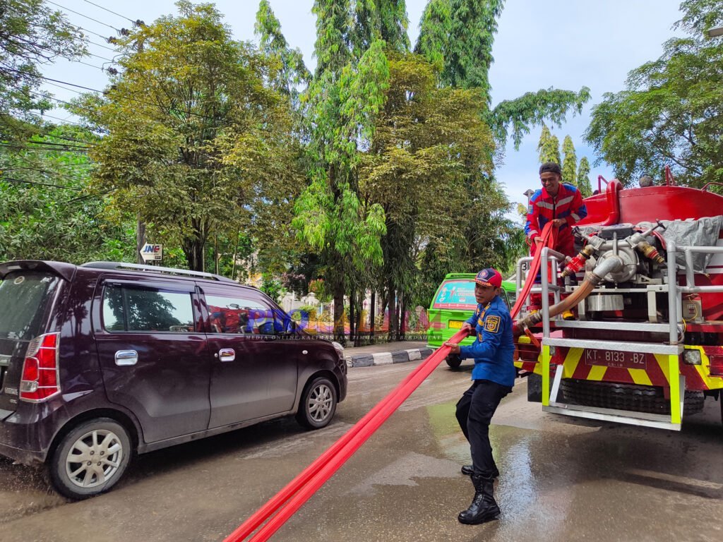 InShot 20220623 110104258 Sedimen Lumpur Meluber, Disdamkar Lakukan Penyemprotan Jalan PROKALTIM